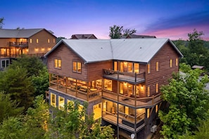 A multi-story wooden building with balconies and large windows, surrounded by greenery. - Mountain View, Private Pool, Theater Room, Hot Tub, & more! - Big Forest Lodge (Sevierville)