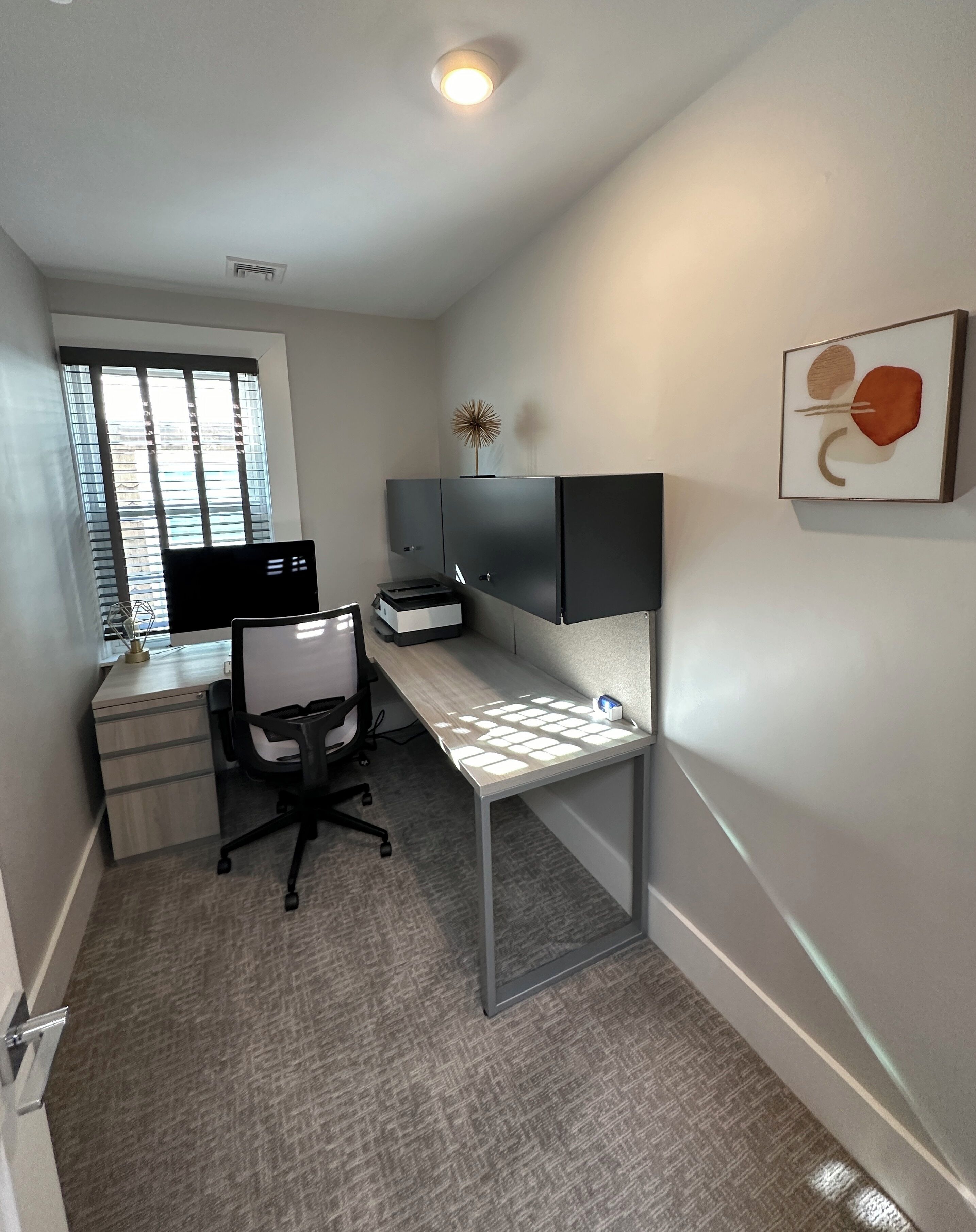 Un espacio de oficina moderno con un escritorio, una silla y un monitor de computadora.