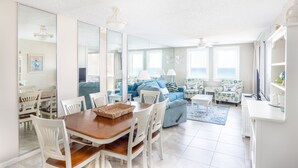Un salón luminoso con comedor, un sofá azul y una televisión.