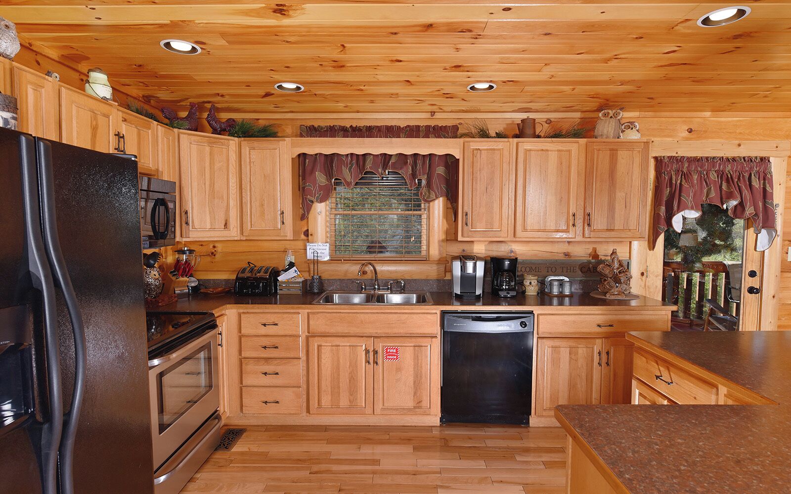 Une cuisine avec des meubles de rangement en bois, un réfrigérateur, un lave-vaisselle et un évier.