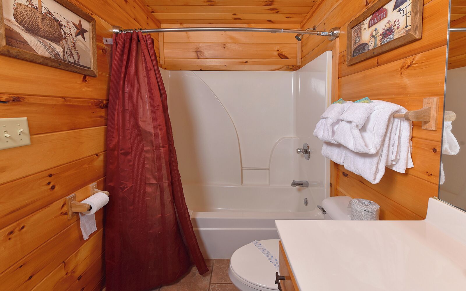 A small, wooden cabin bathroom with a shower, toilet, and sink.