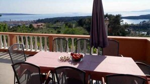 Varanda com mesa posta para dois, oferecendo uma vista panorâmica de um lago e paisagem distante.