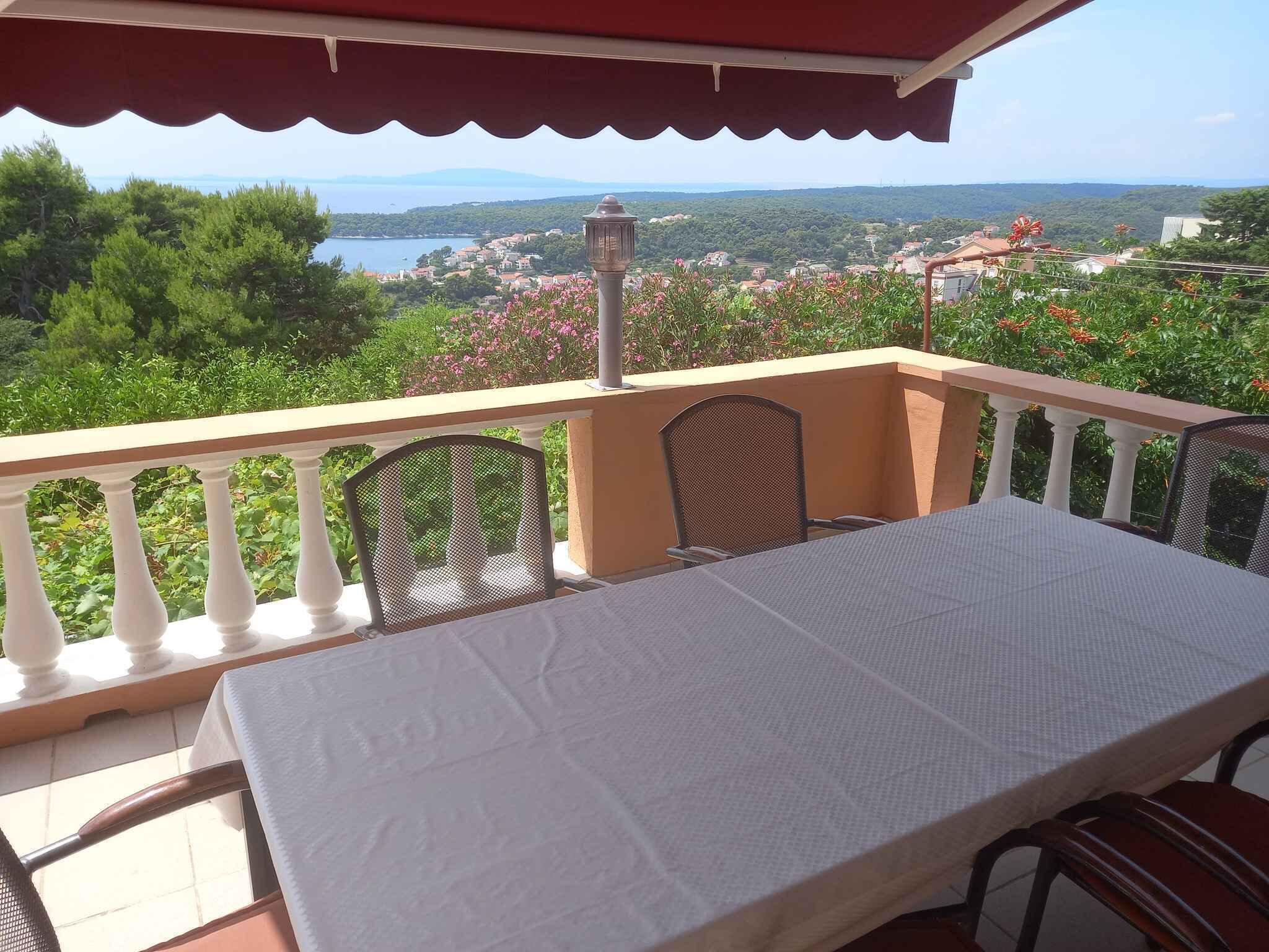 Un balcon avec une table et des chaises, offrant une vue panoramique sur un lac et une ville.