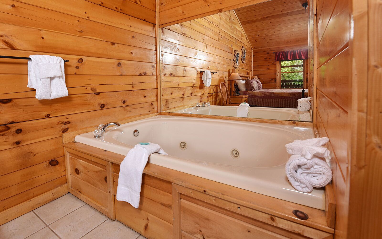 Ein Badezimmer einer Holzhütte mit einer großen Badewanne, Holzschränken und einem Spiegel.