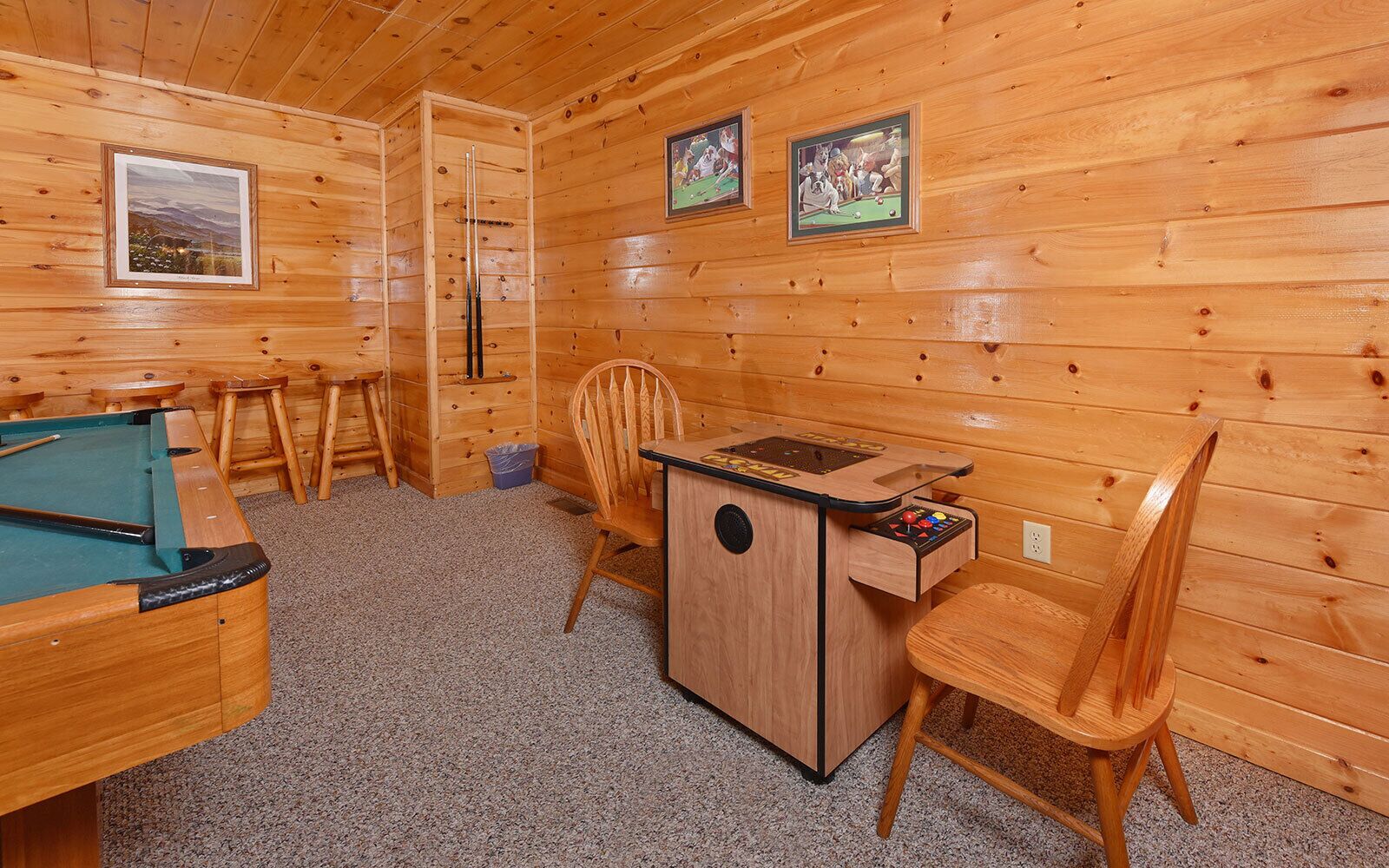 Ein Holzraum mit Billardtisch, Dartscheibe und einem kleinen Tisch mit Stühlen.