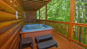 Una terraza de madera con un jacuzzi, dos taburetes y una barandilla de madera.