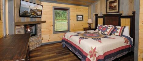 Une chambre confortable avec un lit, une tête de lit en bois, une cheminée et un téléviseur fixé au mur.