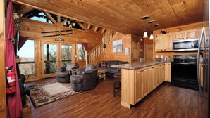 A wooden cabin interior with a kitchen, dining area, and a staircase. - My Runaway Wagon Retreat - Hot Tub & Mountain View (Sevierville)