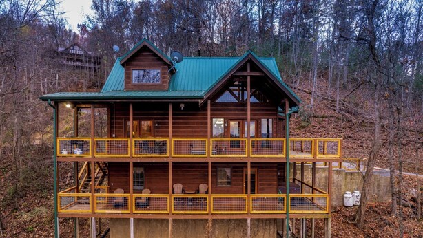 A wooden cabin with a green roof, multiple balconies, and a staircase leading to the upper level. - My Runaway Wagon Retreat - Hot Tub & Mountain View (Sevierville)