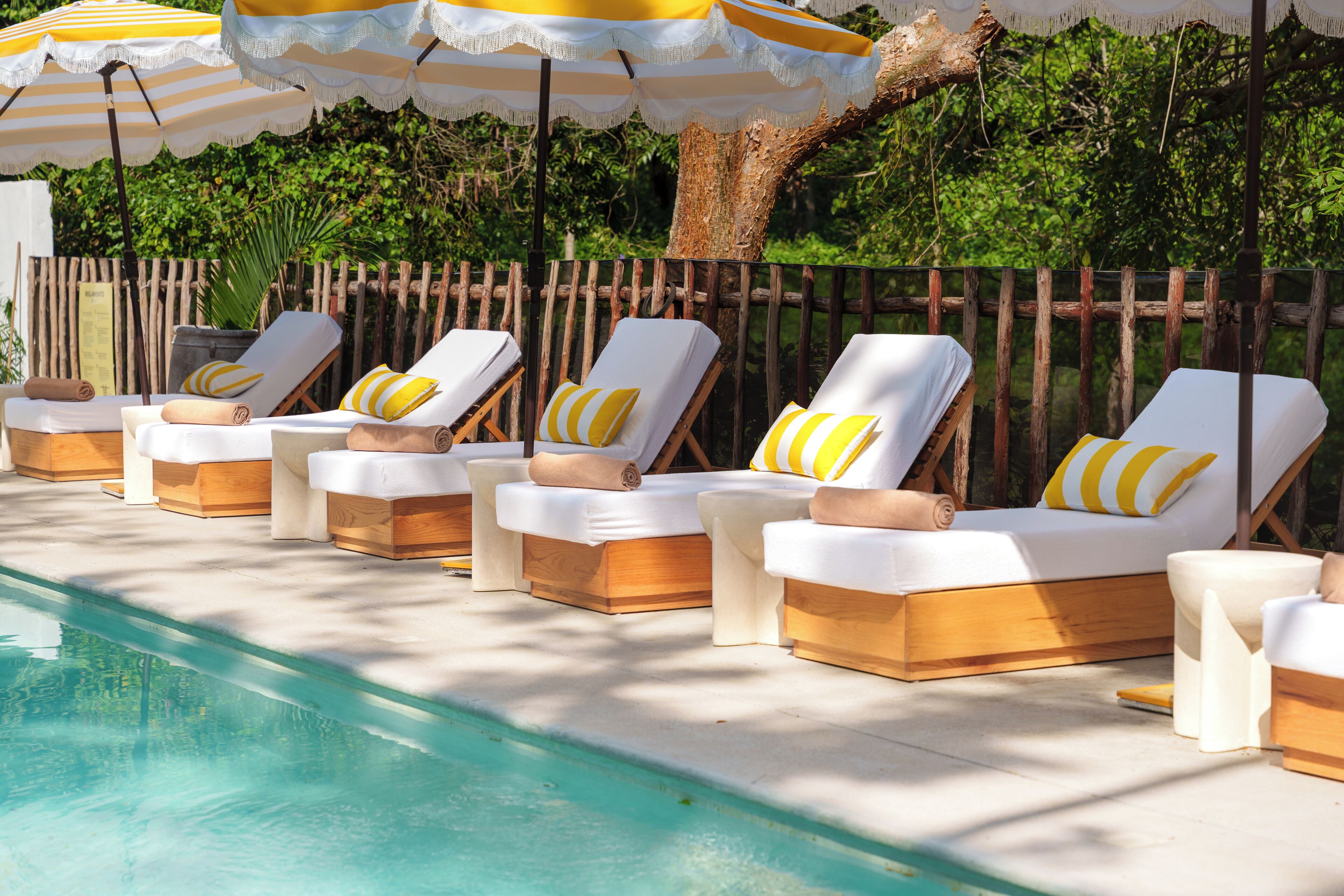 A poolside area with sun loungers and striped umbrellas.