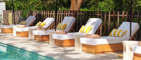 A poolside area with sun loungers and striped umbrellas.