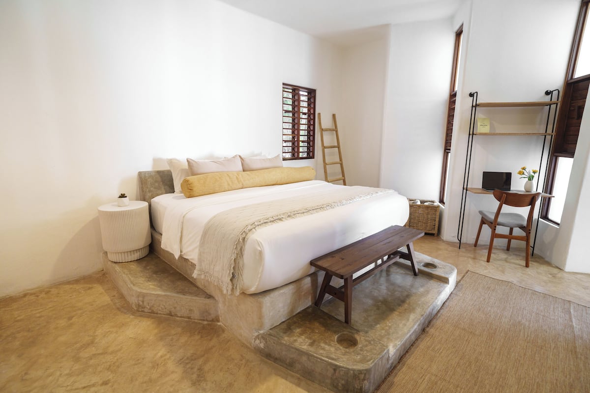 Une chambre à coucher avec un lit, une échelle en bois, un bureau et une chaise.