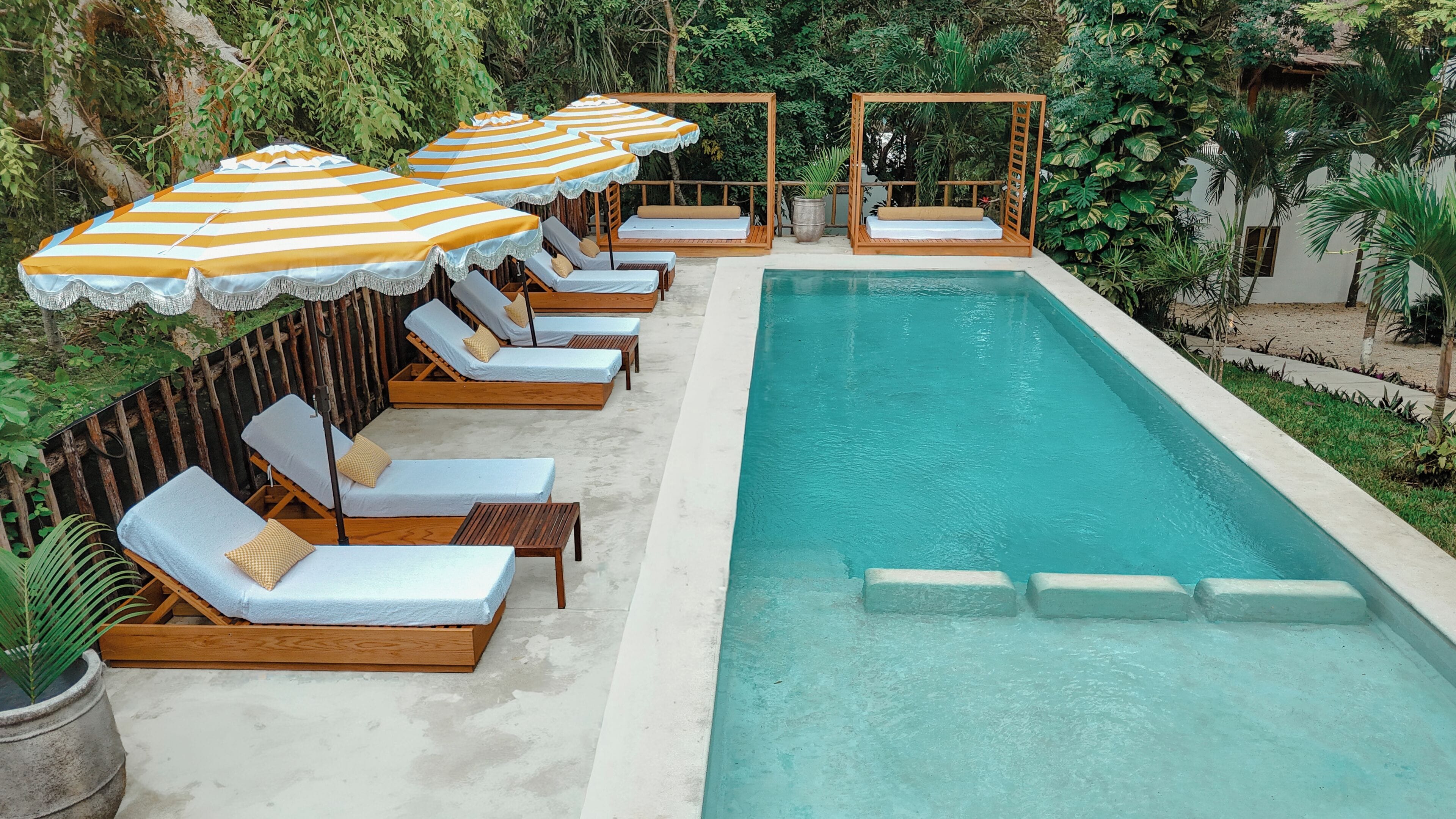 Una piscina al aire libre, sombrillas, sillones reclinables de piscina