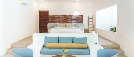 Un salon moderne comprenant un canapé, deux fauteuils, une table basse et un escalier menant à une chambre.