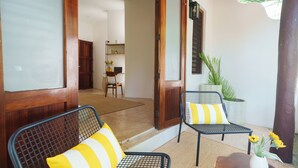 A room with two metal-framed chairs with yellow and white striped cushions, a wooden table with a vase of yellow flowers, and a potted plant. - Mikasa Bacalar Hotel Boutique, Lagoon Front (Bacalar)