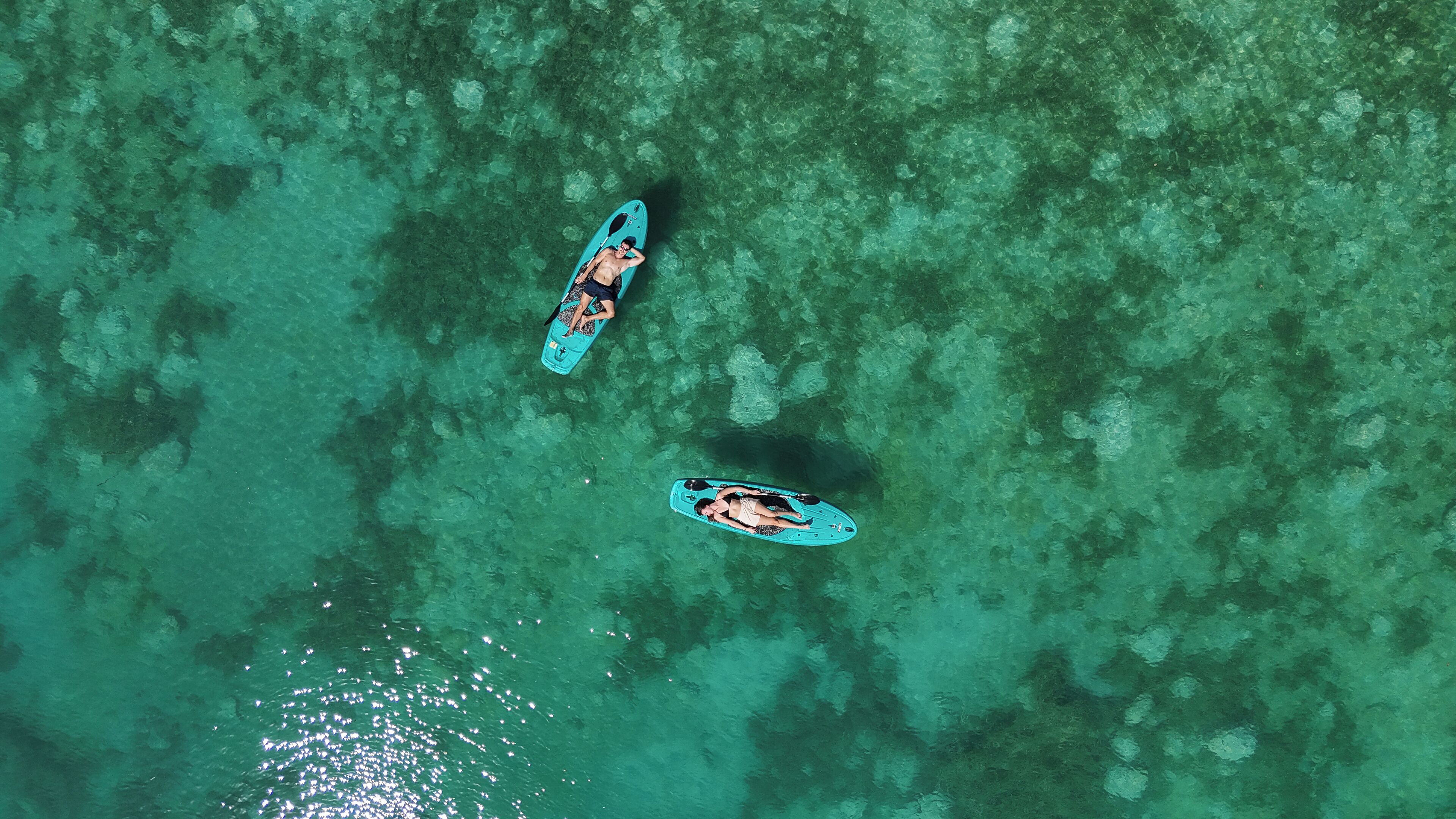 Vue aérienne de deux bateaux sur une eau turquoise et limpide.
