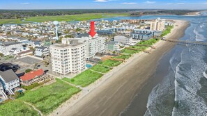 Zona residencial costera con propiedades frente al mar, un tanque de agua grande y un muelle que se adentra en el agua.