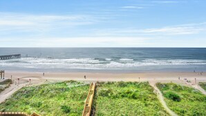 A beach with a wooden walkway leading to a pier.