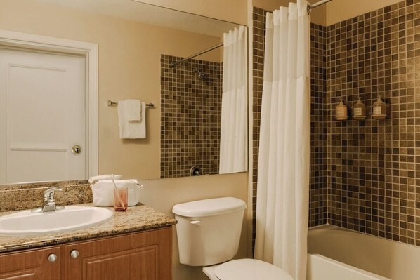 A bathroom with a sink, toilet, and shower area.