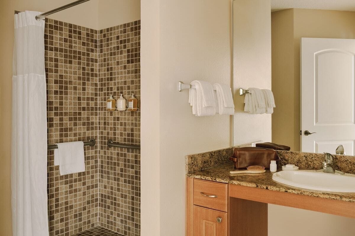 A bathroom with a shower, a sink, and a mirror.