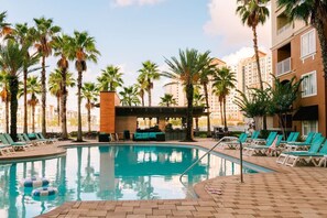 A swimming pool with lounge chairs and palm trees.