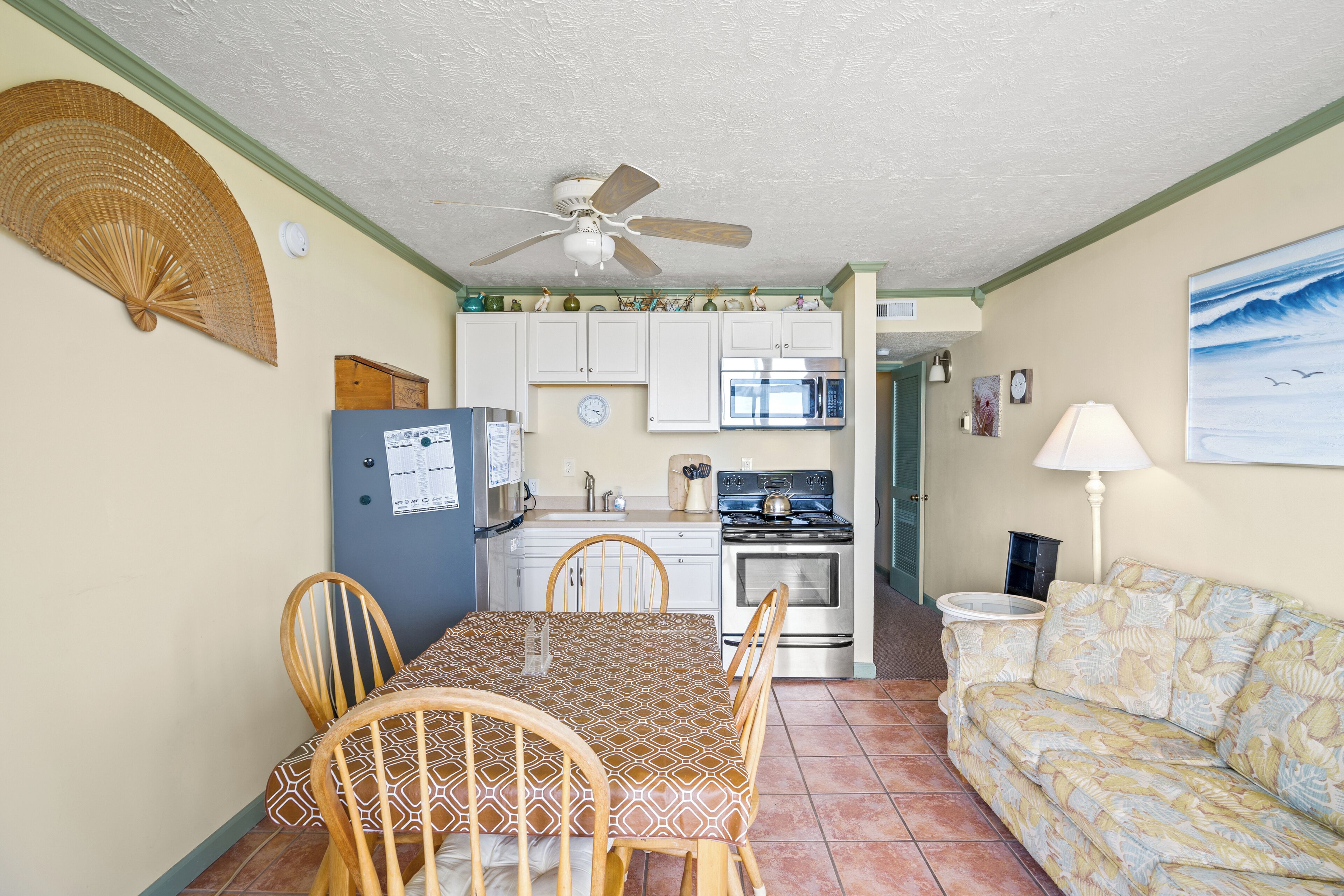 A compact kitchen with a microwave, stove, and dining area with chairs and a table.