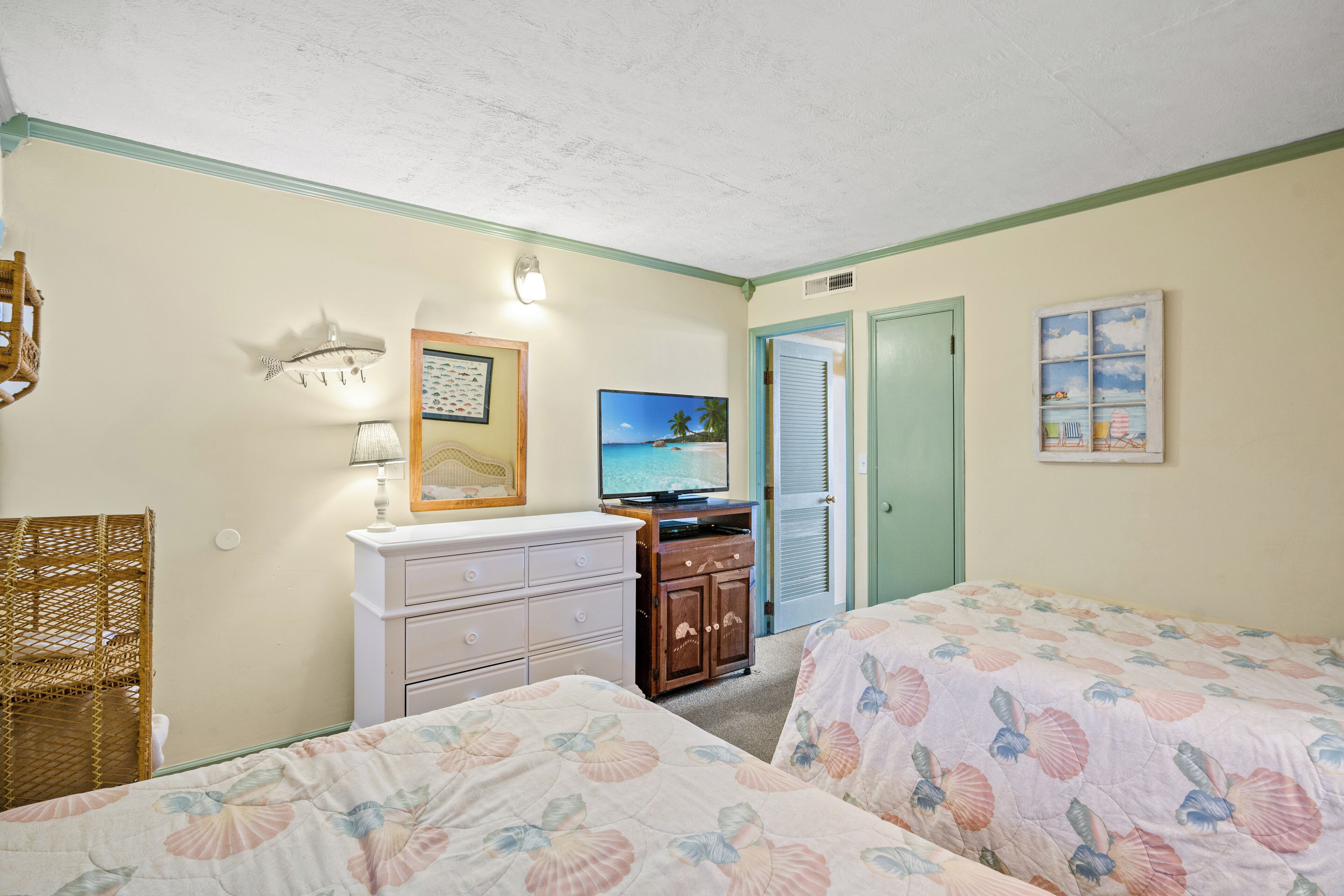 Une chambre avec deux lits, une télévision, une commode et une porte.