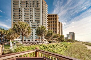 A beachfront hotel with multiple high-rise buildings, a sandy beach, and palm trees.