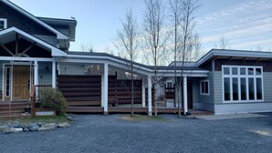 Une maison moderne dotée d’un porche abrité, d’une terrasse en bois et d’une allée gravillonnée.