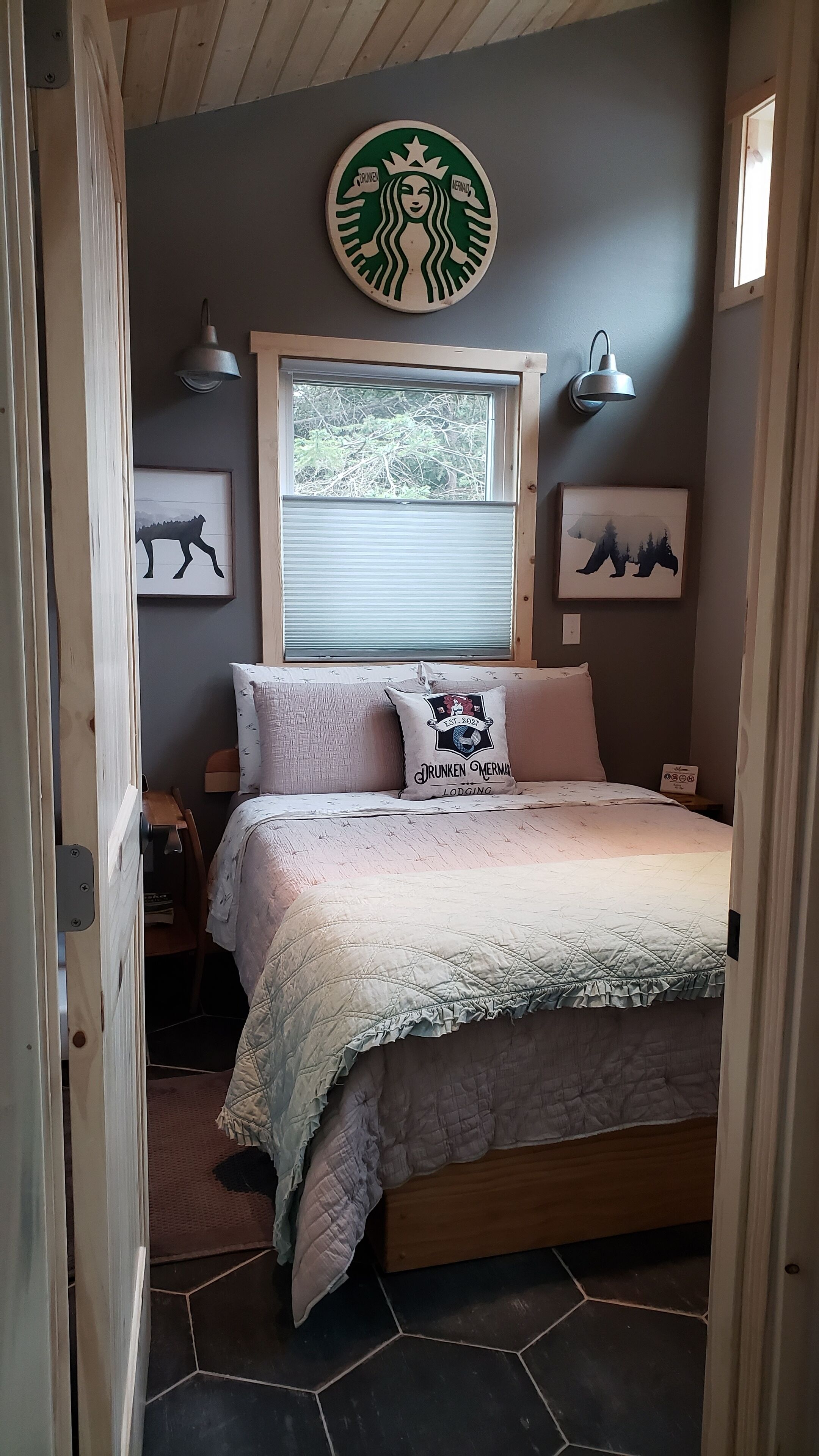 A bedroom with a bed, a window, wall art, and a lamp.