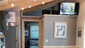 Une pièce chaleureuse avec un plafond en bois, un sol carrelé en pierre, un lit, une chaise et un téléviseur fixé au mur.