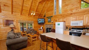 Interior de una cabaña de madera con sala de estar, cocina y comedor.