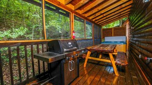 Una terraza de madera con una parrilla, una mesa de picnic y un jacuzzi.