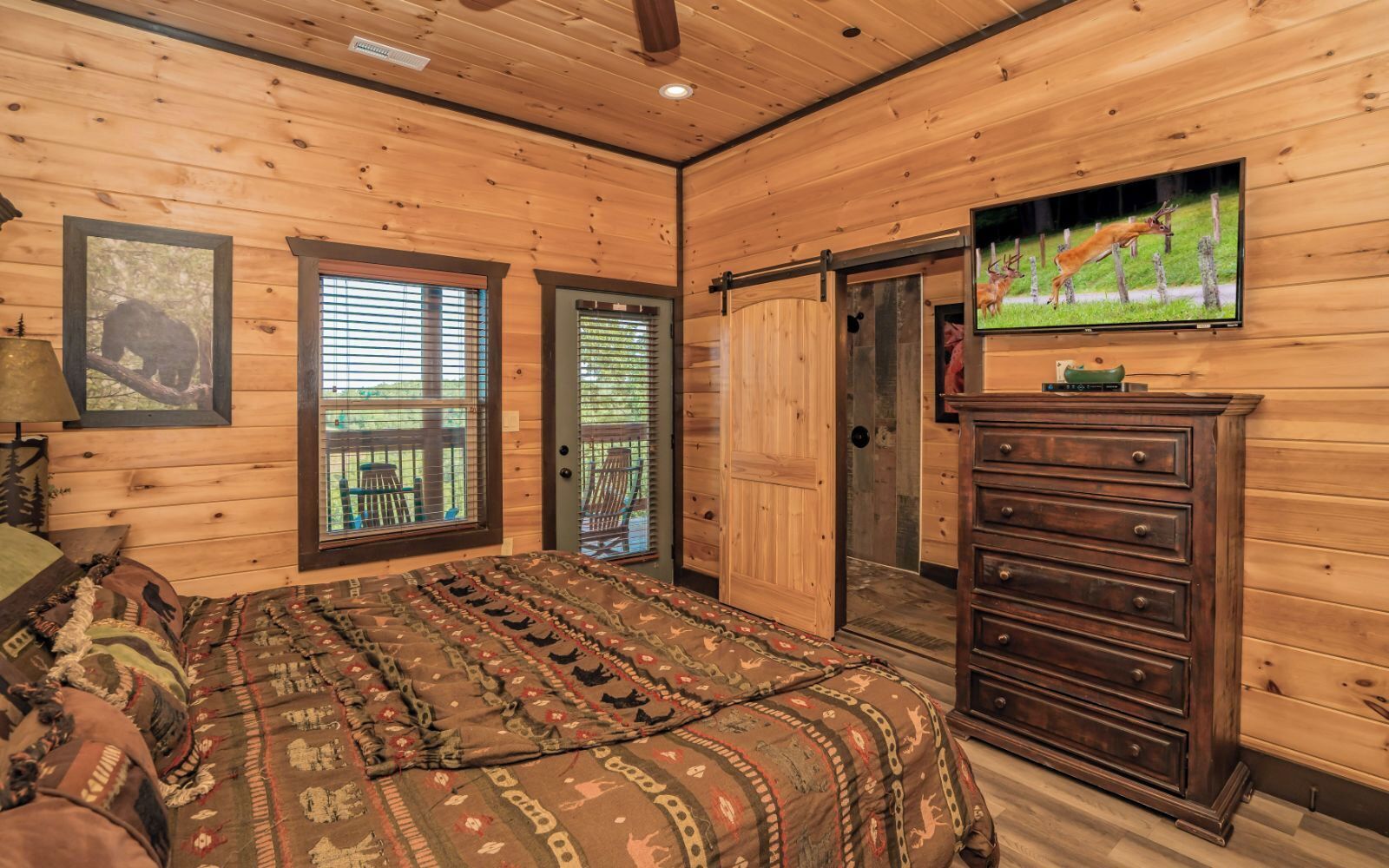 A wooden-paneled room with a bed, dresser, and a television on the wall.