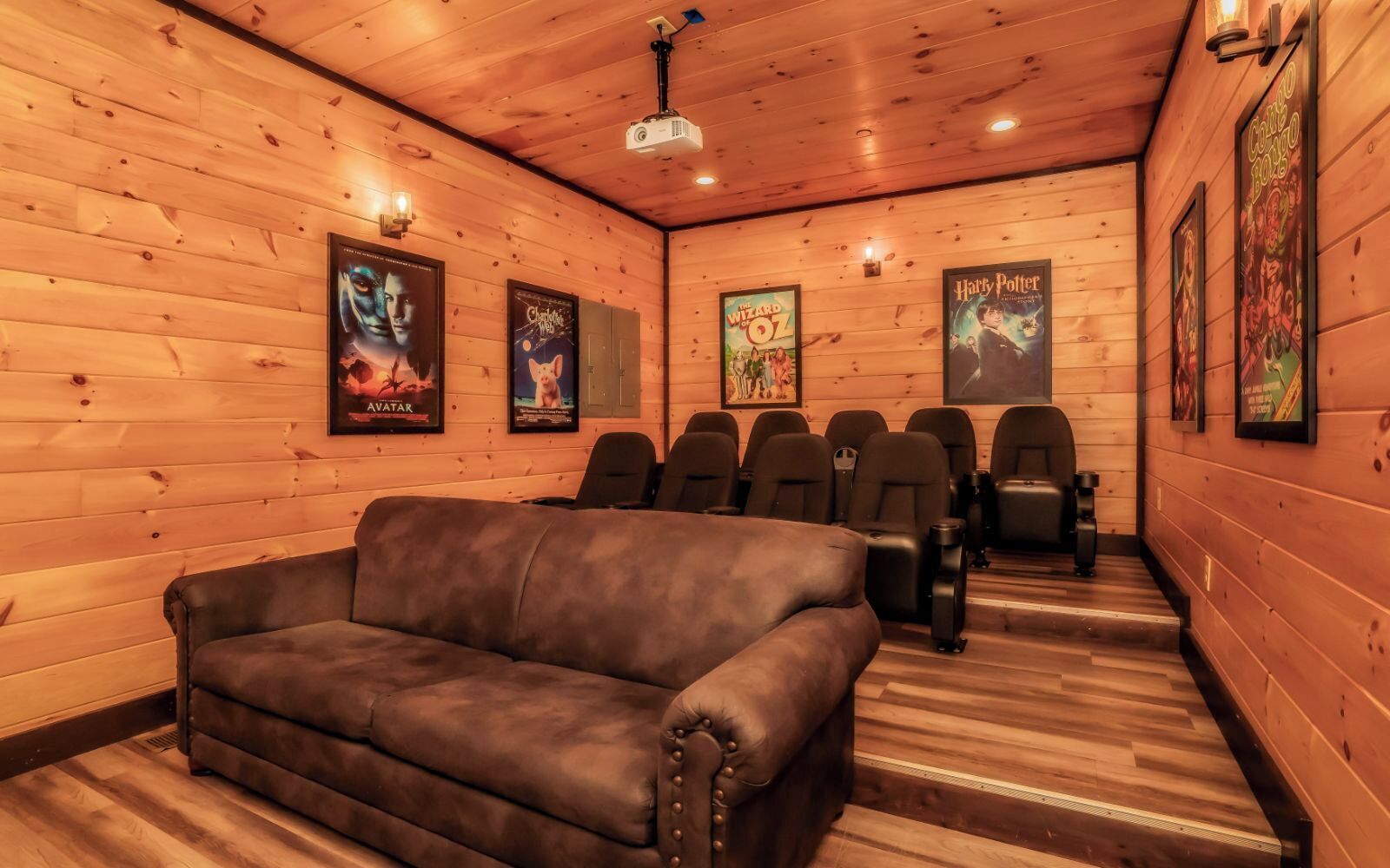 A cozy room with wooden walls, a brown leather couch, and several black chairs.
