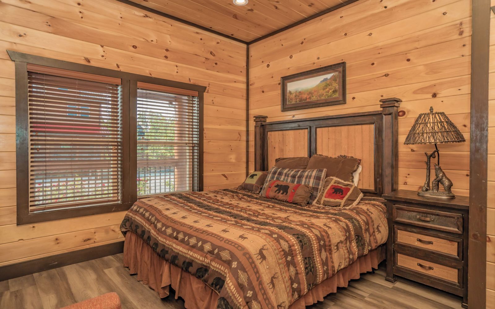 Un dormitorio con paneles de madera, una cama, una mesita de noche, una lámpara y un cuadro en la pared.