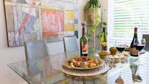 A dining table with a glass top, surrounded by chairs, and a colorful abstract painting on the wall. - 4BR, Private Backyard Oasis/POOL & HotTub(Jacuzzy) (Hollywood)
