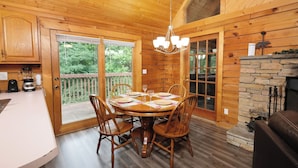 A wooden cabin interior with a dining table set for four, surrounded by wooden chairs. - Heaven on Earth - Pet Friendly & Secluded (Sevierville)
