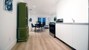 Una cocina moderna con armarios blancos, una estufa negra y una zona de comedor con mesa y sillas.