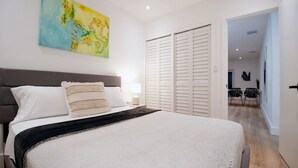 Un dormitorio con cama, un cuadro, un armario y un pasillo que conduce a otra habitación.