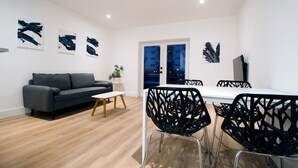 Una sala de estar moderna con un sofá, una mesa de comedor con sillas y arte abstracto en las paredes.