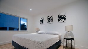 A modern bedroom with a large bed, a nightstand, and three abstract wall art pieces. - Modern Apart beside canal, near beach w/parking (Sunny Isles Beach)