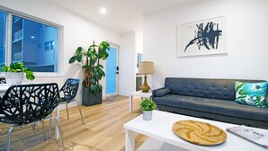 A modern living room with a grey sofa, black chairs, a white coffee table, and a large abstract painting. - Modern Apart beside canal, near beach w/parking (Sunny Isles Beach)