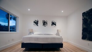 Un dormitorio moderno con una cama grande, una ventana con vistas y arte abstracto en la pared.