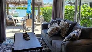 A room with a sofa, a coffee table, a view of a pool and outdoor seating area. - Waterfront Bring Your Boat Cabana Club Membership Included (Key Colony Beach)