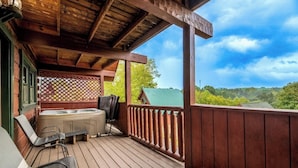 A wooden deck with a hot tub, chairs, and a view of a green landscape. - Above It All - Pet Friendly, 3 Mi to Dollywood, Hot Tub + Pool Table & Games (Sevierville)