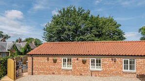 A brick building with a tiled roof, a gravel driveway, and a wooden gate. - 1 bedroom accommodation in Fulletby, near Horncastle (Fulletby, near Horncastle)