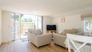 A spacious living room with a sofa set, a television, and a dining area with a table and chairs.