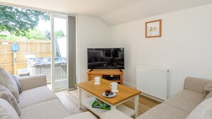 Een woonkamer met een bank, een houten salontafel, een televisie en een radiator.