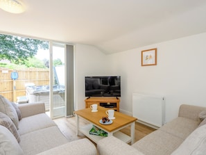 A living room with a sofa, a wooden coffee table, a TV, and a radiator.